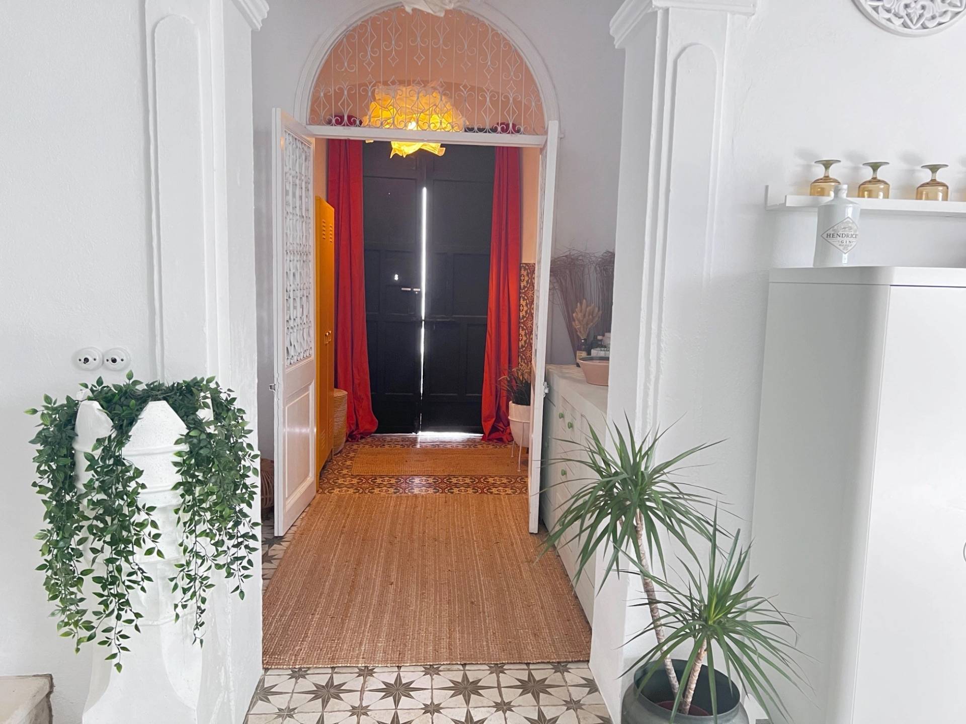 Entrance hallway film location in Calle Sevilla Jimena de la Frontera by Love Locations, featuring wood-look flooring, white archways, and a vibrant red accent feature door.