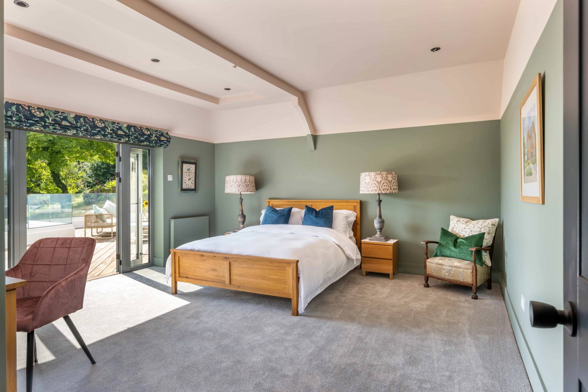 Elegantly styled bedroom suite with soft sage green walls, wooden bed frame, and countryside garden views, ideal for mattress and sleepwear brand ads, Love Locations.