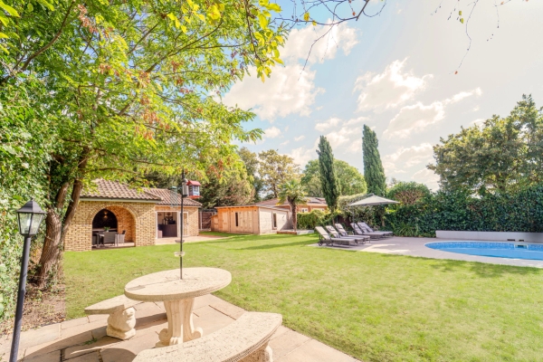Garden stone bench dining set on manicured lawns looking towards an outdoor swimming pool terrace, Love Locations RM11.