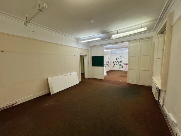 Corner view of a vast, empty dilapidated room with classic double doors for film and television production, curated by Love Locations.