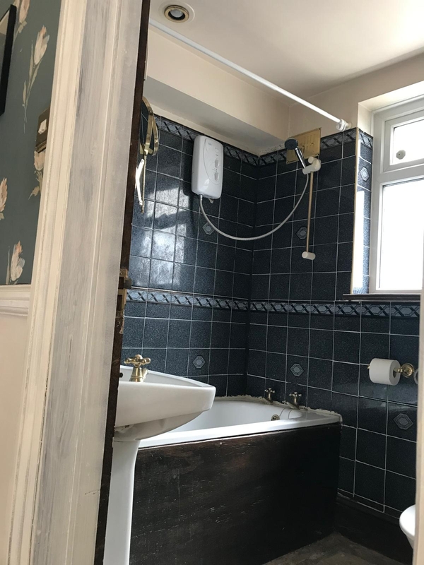 Retro family bathroom location featuring deep blue wall tiles, a classic white basin, and an integrated bath unit, great for period narrative filming, Love Locations SE25.