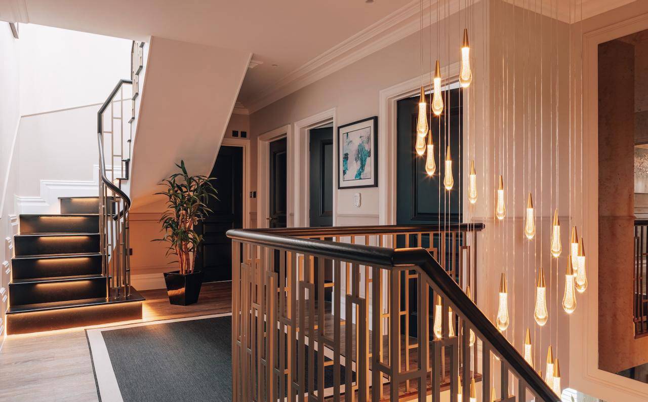 Upper stairwell landing with hanging glass pendant teardrop chandeliers and dark wood balustrades, Love Locations.