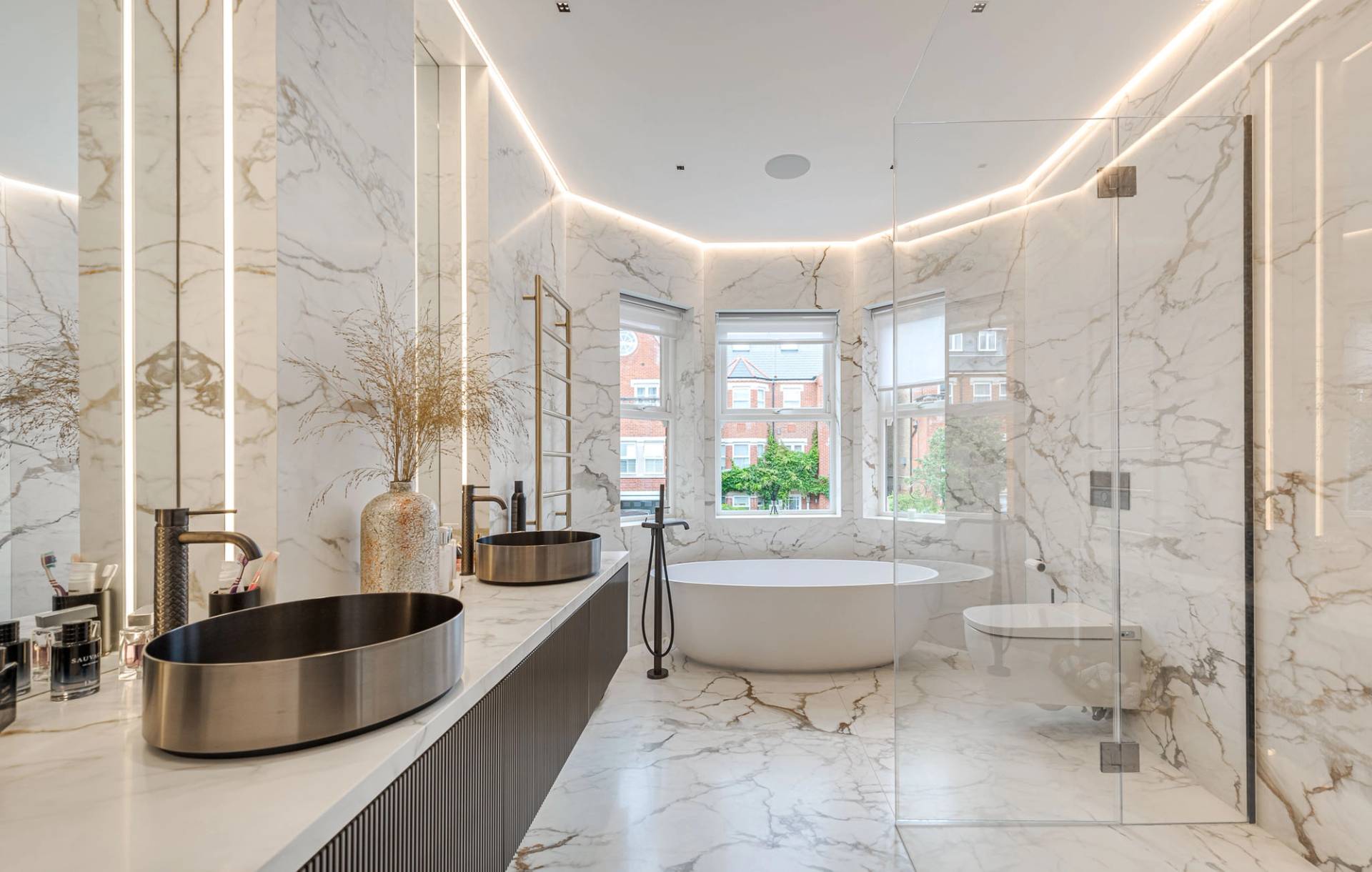 Luxury marble bathroom with a freestanding bathtub set into a curved bay window alcove, Love Locations SW11.