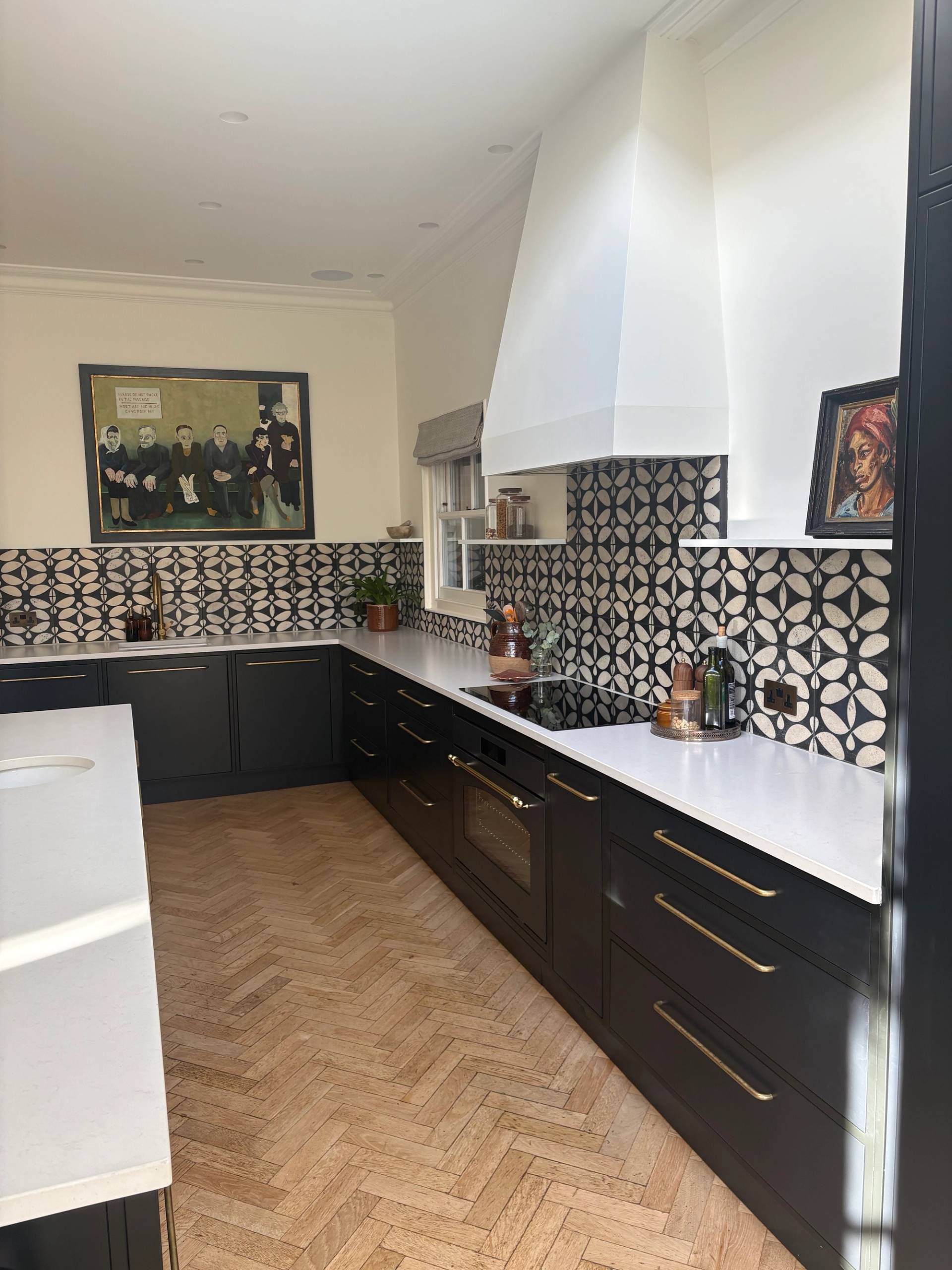 Spacious kitchen shoot location featuring dark lower cabinets, herringbone parquet flooring, white chimney hood, and geometric pattern wall tiles by Love Locations.