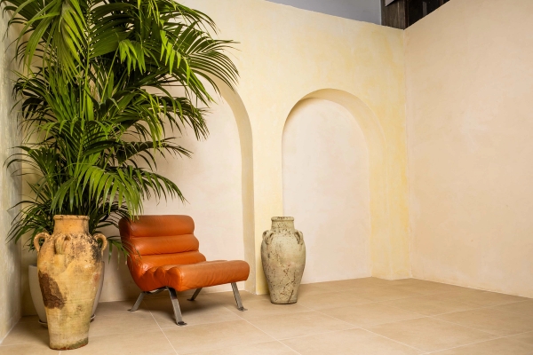 Plaster arch backdrop set with tropical potted palm, rustic urn, and orange leather armchair in a North London studio, Love Locations N15.