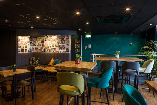 Upstairs bar corner setup featuring vibrant teal upholstery, dark walls, and photo gallery collages, ideal for commercial pop culture filming, Love Locations.
