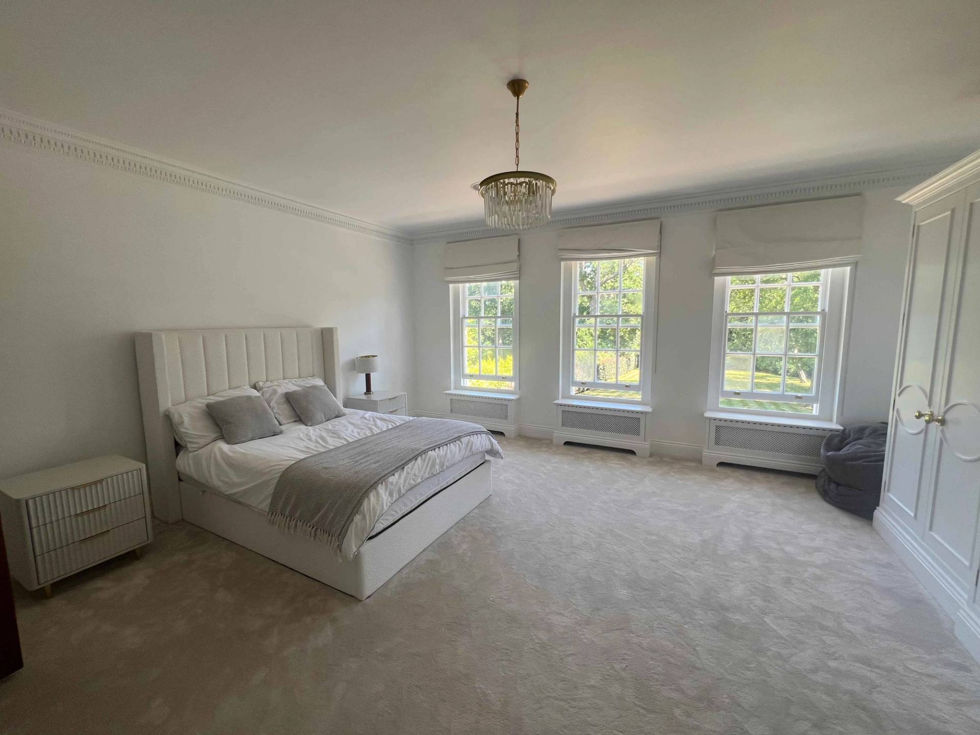 Master bedroom with cream upholstered bed, sash windows, and neutral carpet flooring, Love Locations BR7.