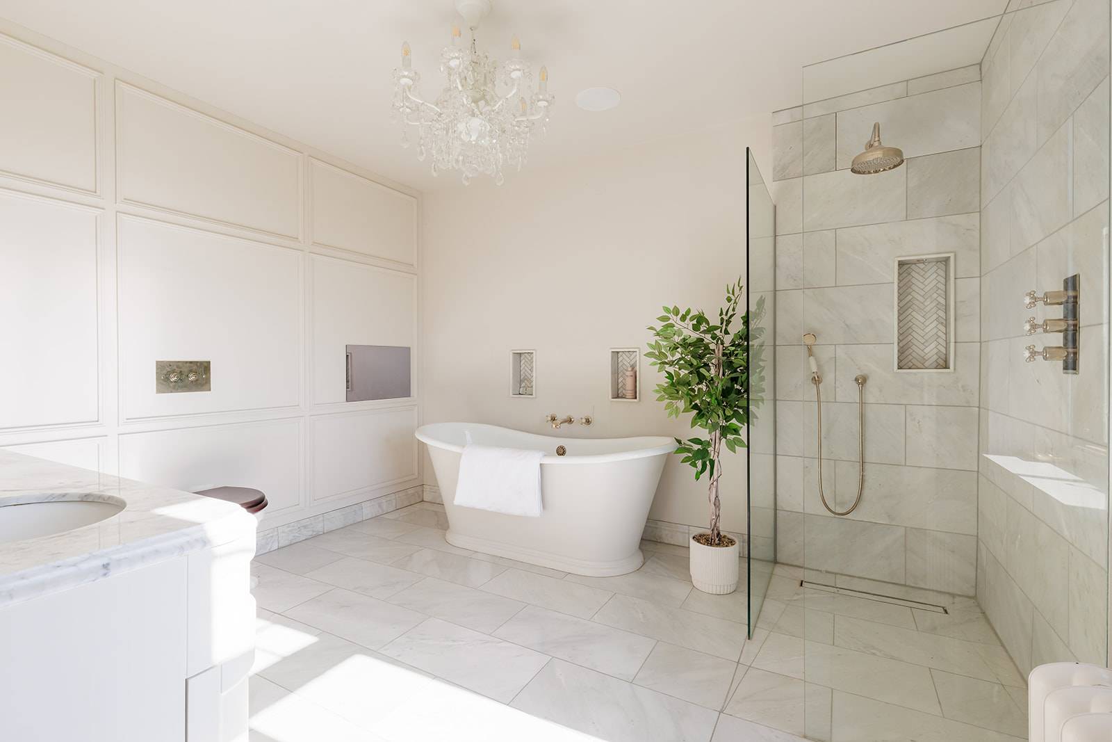 Luxury ensuite bathroom featuring a freestanding oval bathtub, walk-in glass shower, and marble tiles, Love Locations RH13.