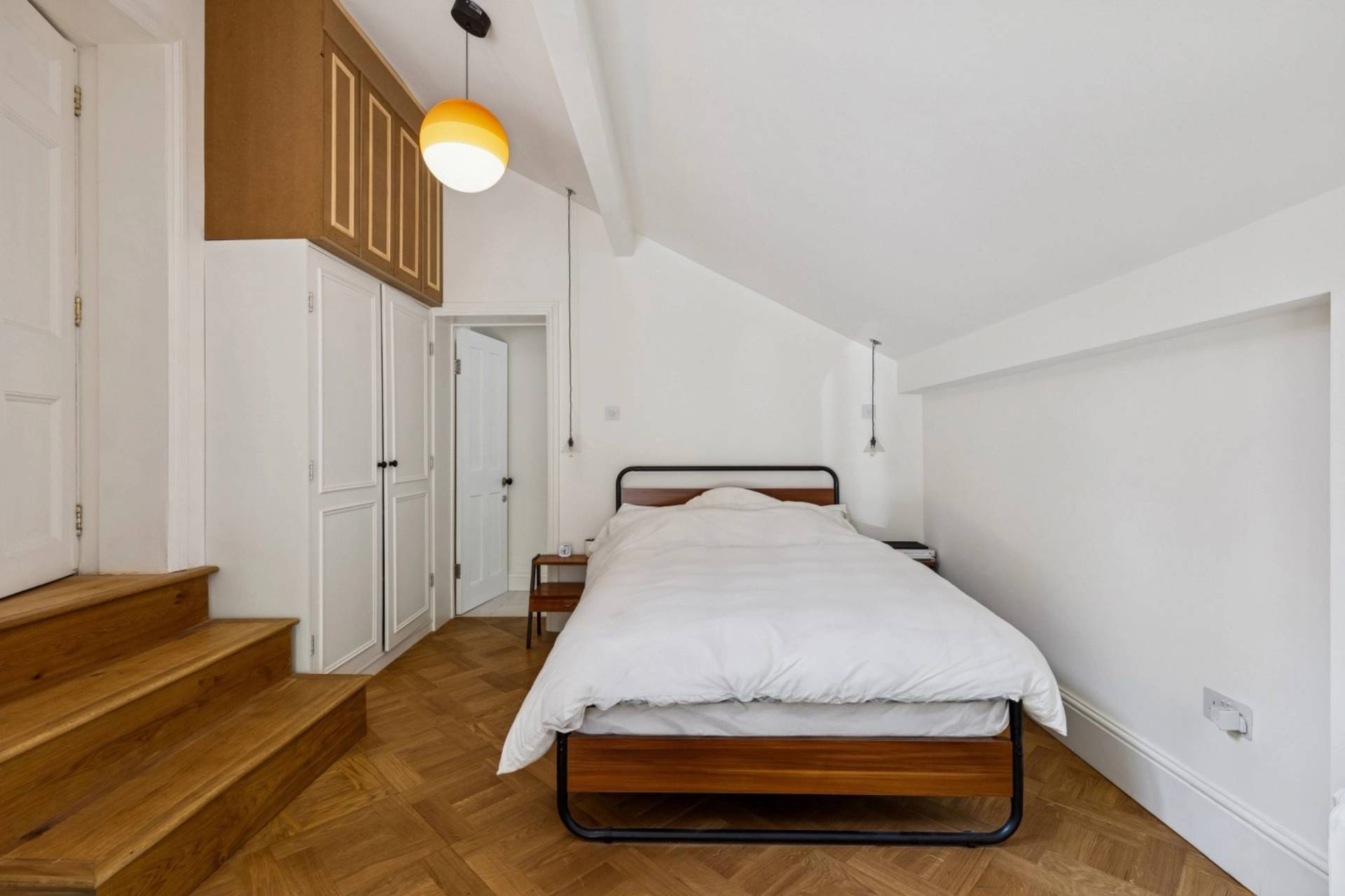 Attic bedroom with sloped ceilings and light wood floors in a gothic Hampstead property from Love Locations.