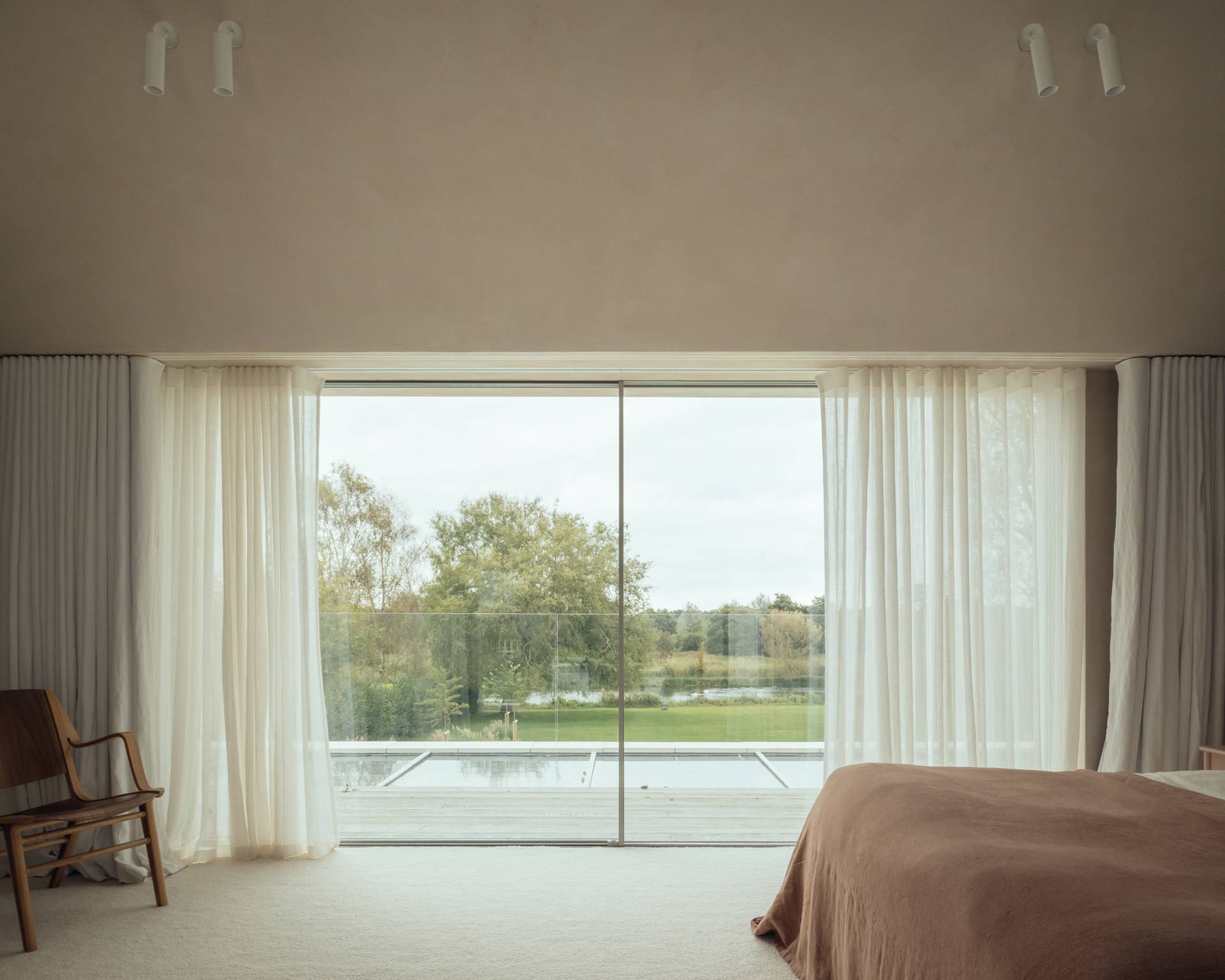 Sunlit master bedroom with panoramic glass doors overlooking the Hampshire countryside, perfect for high-end sleepwear brand shoots, Love Locations SO20.