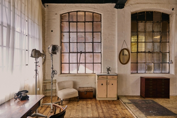 Historic industrial warehouse window backdrop with vintage cream cabinets, vintage mirrors, and industrial lights, perfect for brand advertising, Love Locations.