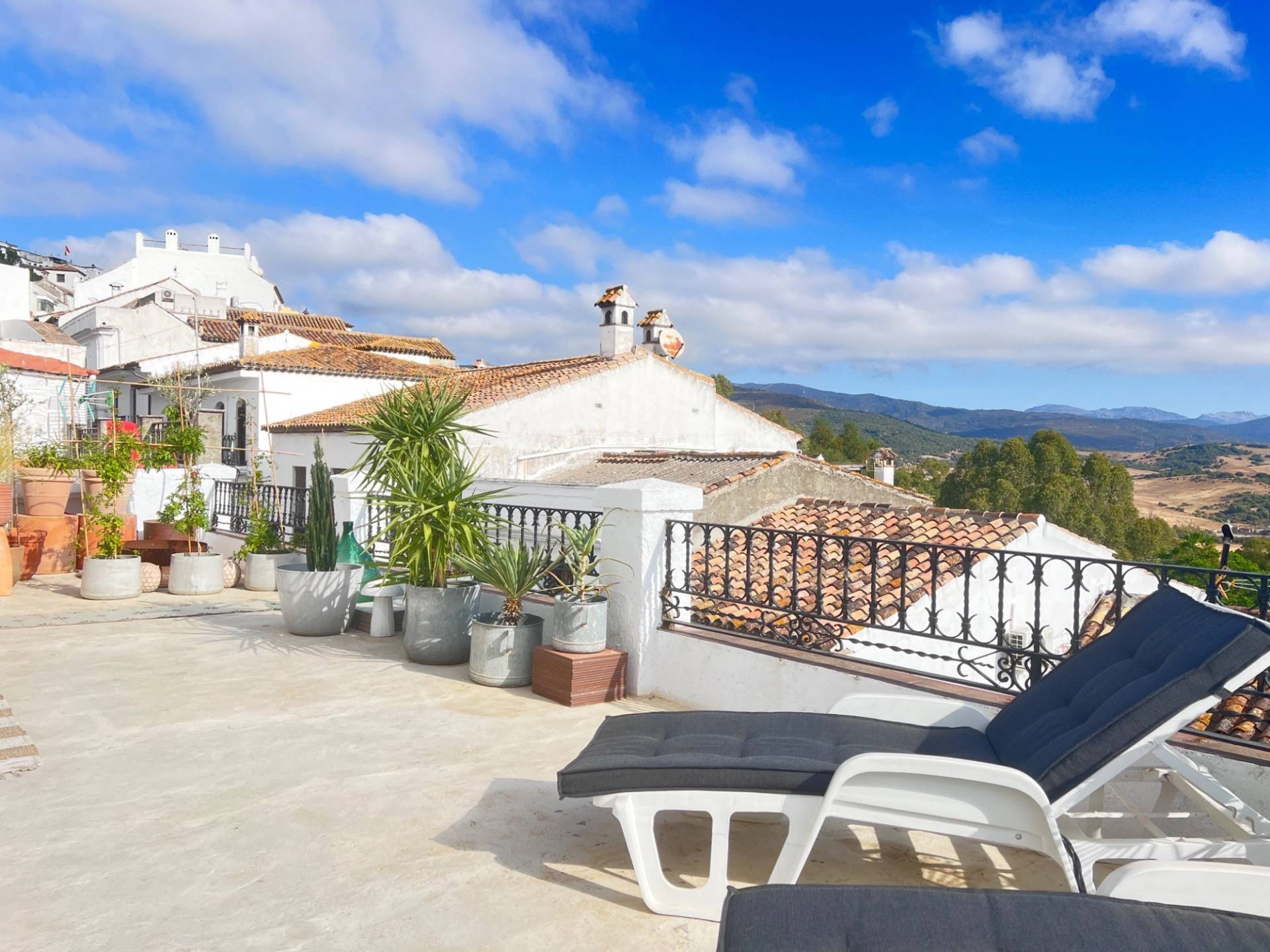 Traditional Andalucian roof terrace film location in Calle Sevilla Jimena de la Frontera via Love Locations, showcasing terracotta tiled roofs, sun loungers, and scenic hilltop vistas.
