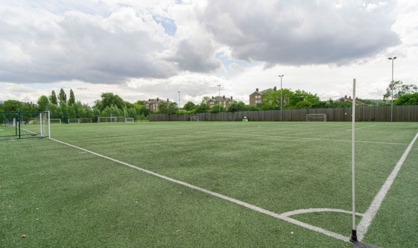 Love Locations synthetic turf location London SE2: Wide-open all-weather football and hockey ground surrounded by boundary fencing, ideal for sports action sequences.