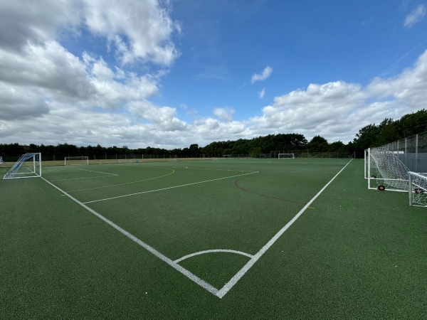 Love Locations outdoor sports pitch Cockfosters EN4: Green all-weather artificial turf football field showing side lines and a white target line layout, tailored for sportswear campaigns.