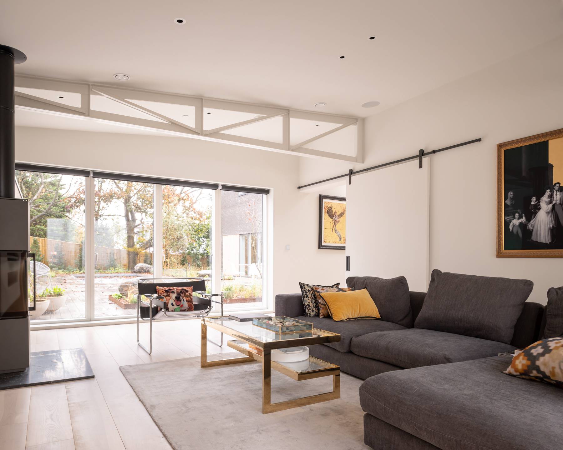 Modern living room with a grey L-shaped sectional sofa, glass coffee table, and courtyard garden views, Love Locations BN3.