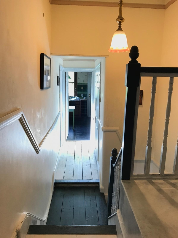 Looking down a narrow domestic corridor toward a bright kitchen workspace in a Croydon location house, Love Locations SE25.