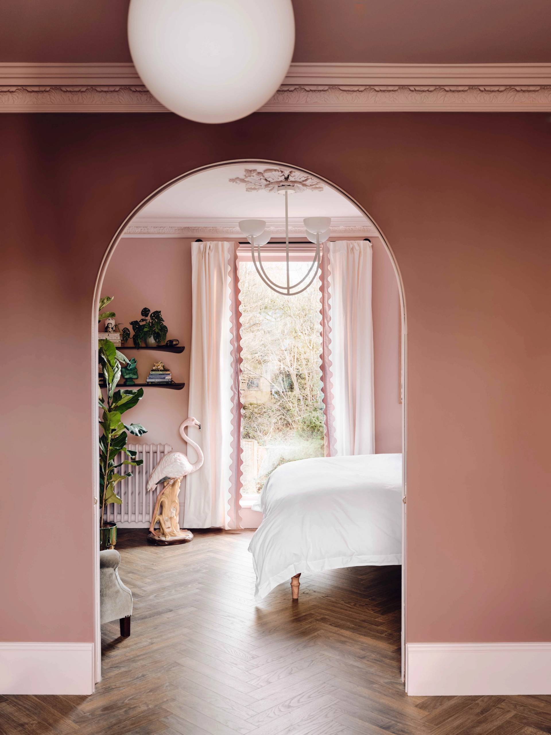 Master bedroom suite looking through a bespoke pink arch door onto a white bed and flamingo floor ornament, Love Locations CR0.