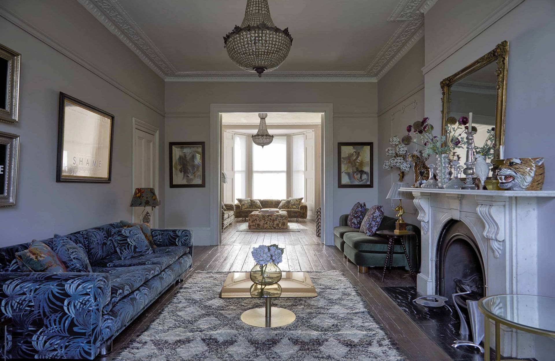 Symmetrical reception shot featuring a blue patterned sofa, geometric rug, and large blue vintage travel poster, Love Locations N16.