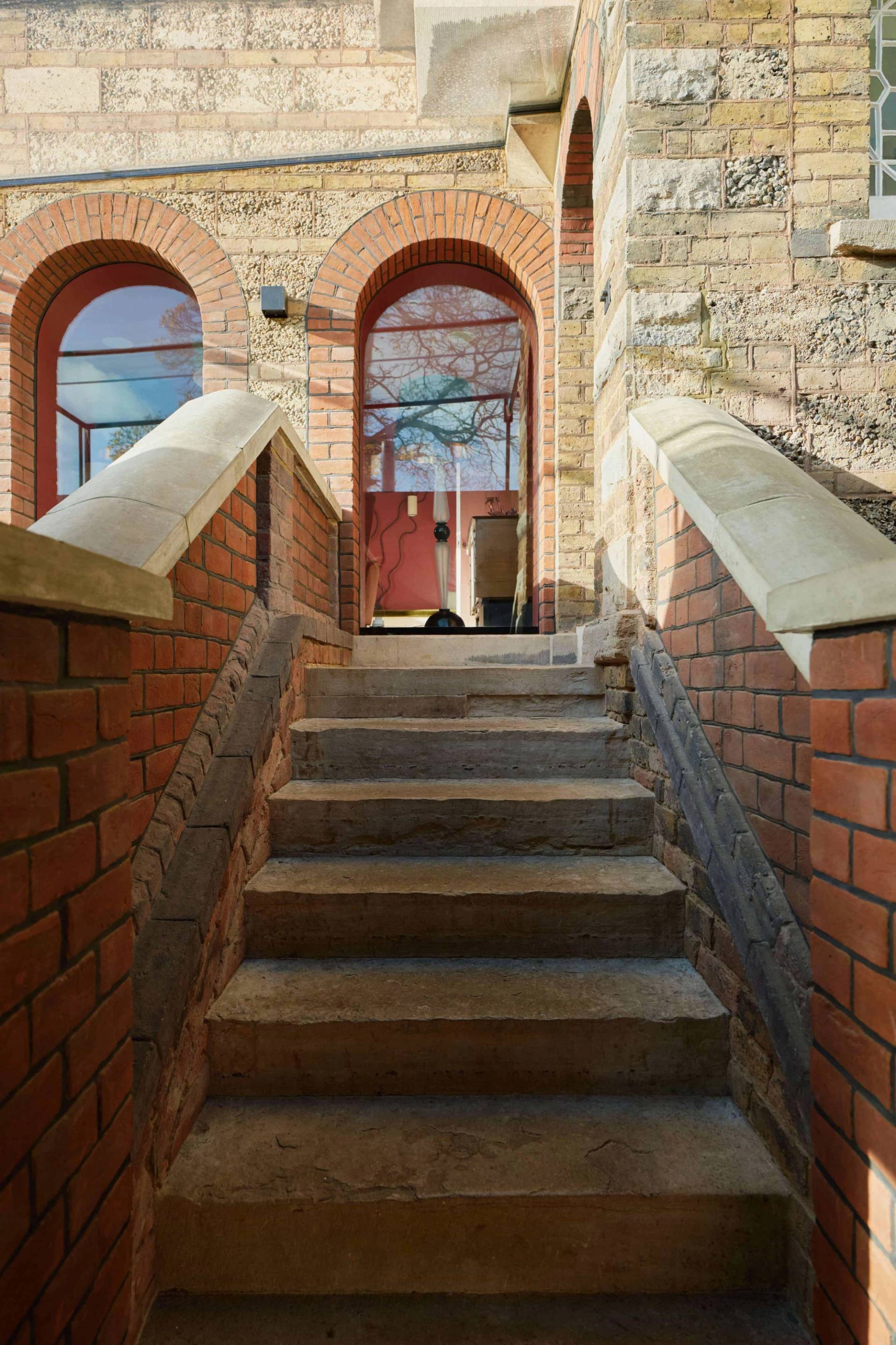 Stone steps leading up past yellow brick retaining walls to a elevated garden terrace, Love Locations.