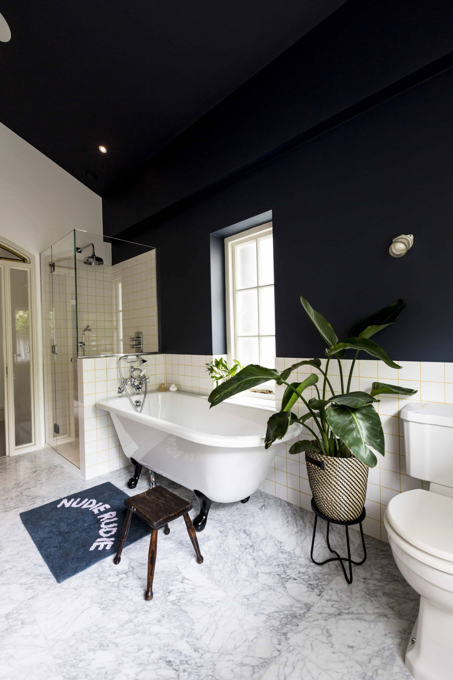 White freestanding bathtub in a navy pitched roof attic bathroom location in Camberwell, SE5 via Love Locations.