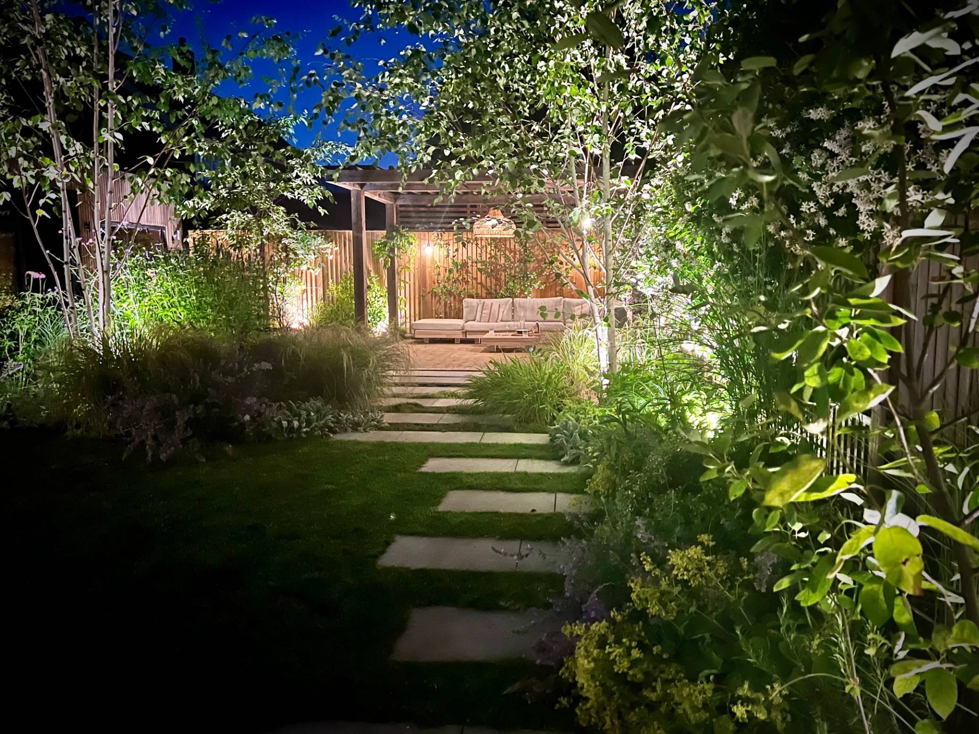Illuminated garden path at night with concrete stepping stone lighting and lush planting, Love Locations TW1.