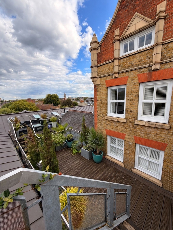 Private timber decking roof terrace on a penthouse shoot location in Brixton SW4, offering outdoor seating and views of the red-brick Victorian school facade via Love Locations.