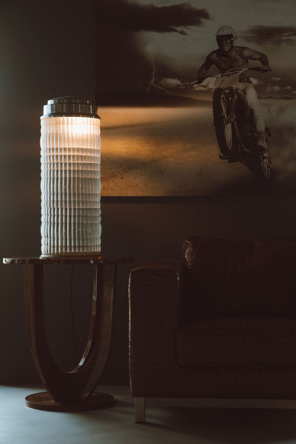Mood-lit lounge corner with modern cylindrical table lamp and textured microcement wall finishes, Love Locations 07630.