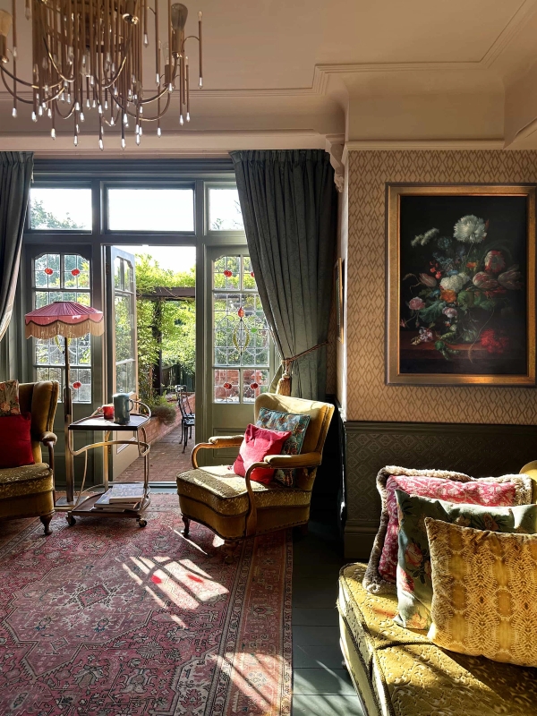 Edwardian reception room filled with sunlight, featuring garden doors, patterned rugs, and period armchairs, Love Locations N13.