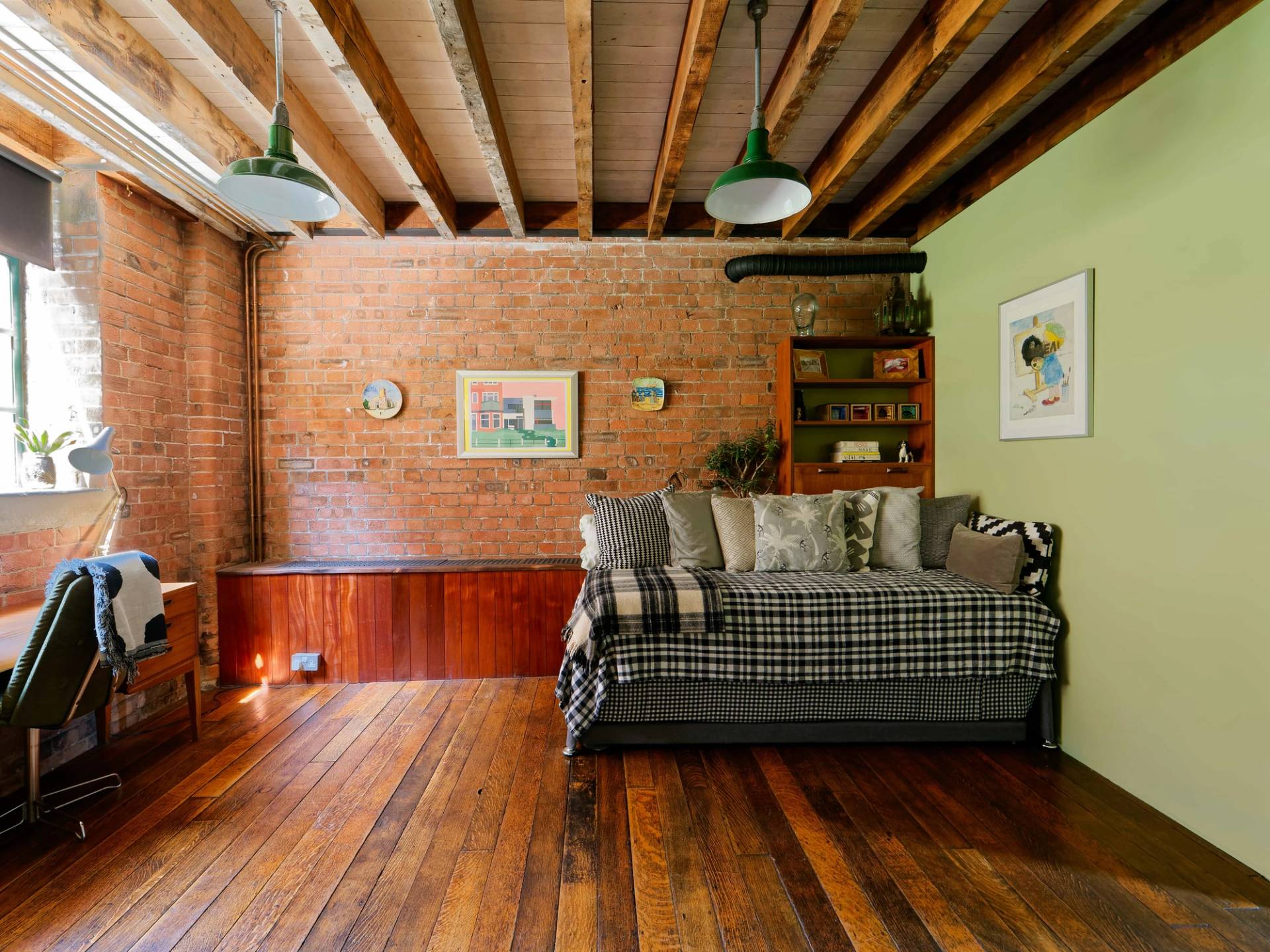 Cozy loft bedroom with exposed timber ceiling joists, exposed red brick walls, and plaid sofa bed, Love Locations E14.