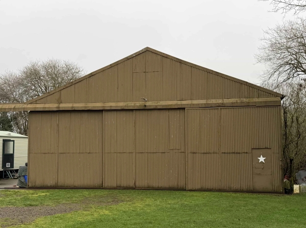 Corrugated metal exterior wall of a historic airfield storage shed, ideal as a raw industrial backdrop for fashion photography, Love Locations.