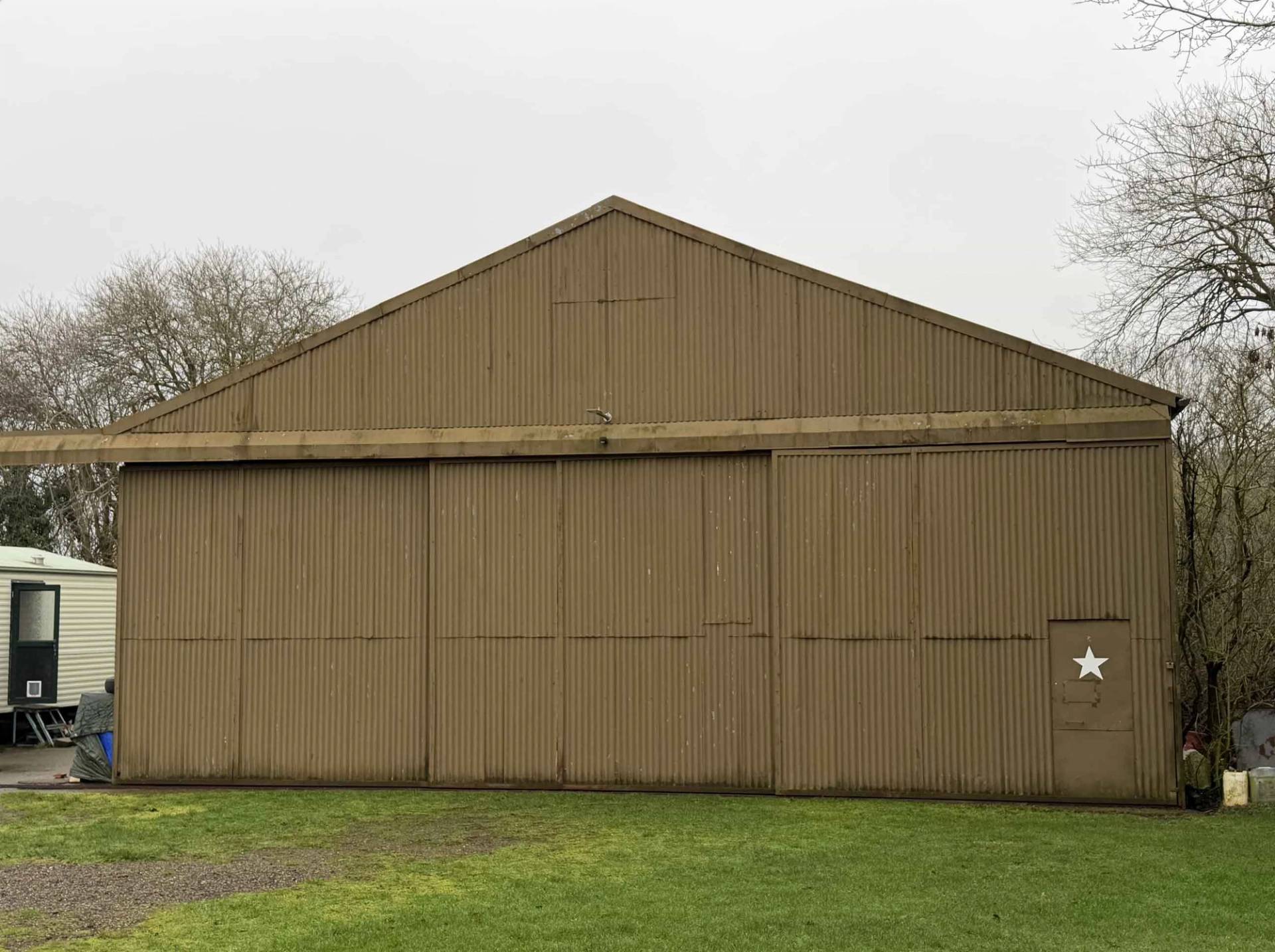 Corrugated metal exterior wall of a historic airfield storage shed, ideal as a raw industrial backdrop for fashion photography, Love Locations.