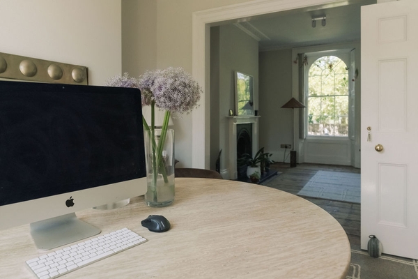 Home office and desk workspace set up on a round wooden table against a backdrop of period sash windows, Love Locations.