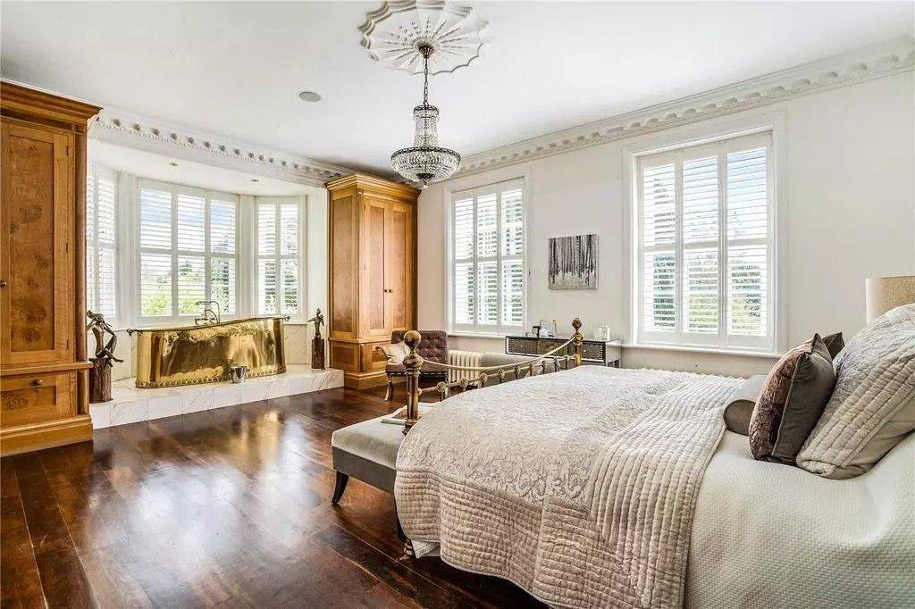 Luxury master bedroom shoot space in Reading RG10 from Love Locations, displaying polished dark hardwood floors, bay sash windows, chandelier, and a plush upholstered bench.