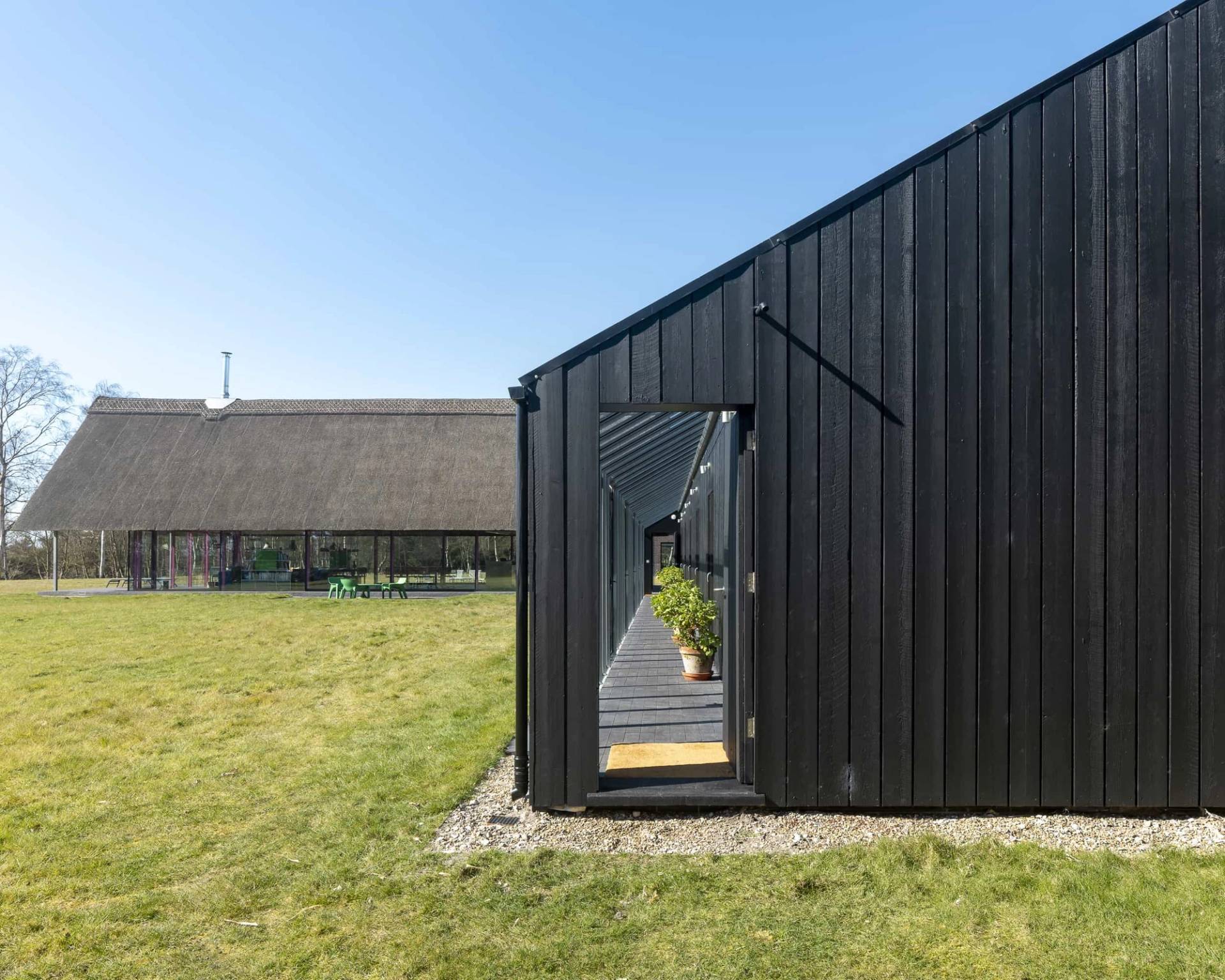 Dark timber outbuilding extension connected to a modern thatched longhouse estate, Love Locations IP17.