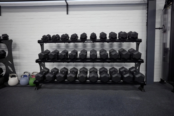 Organized tiers of professional rubber hex dumbbells on heavy-duty storage racks inside a Winchester gym, Love Locations SO23.