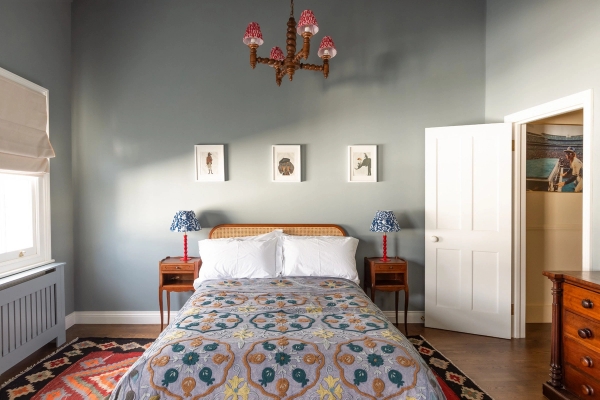 Symmetrical bedroom layout for film and photography hire in Westminster SW1V via Love Locations, showcasing light grey walls, twin lamps, and a patterned bedspread.