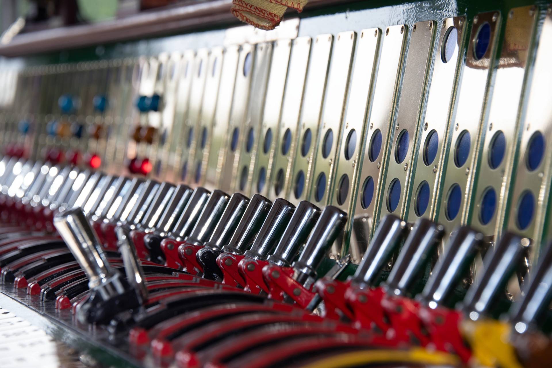 Close-up detail of polished steel mechanical signal box levers in a heritage railway control room, Love Locations TN22 3QL.