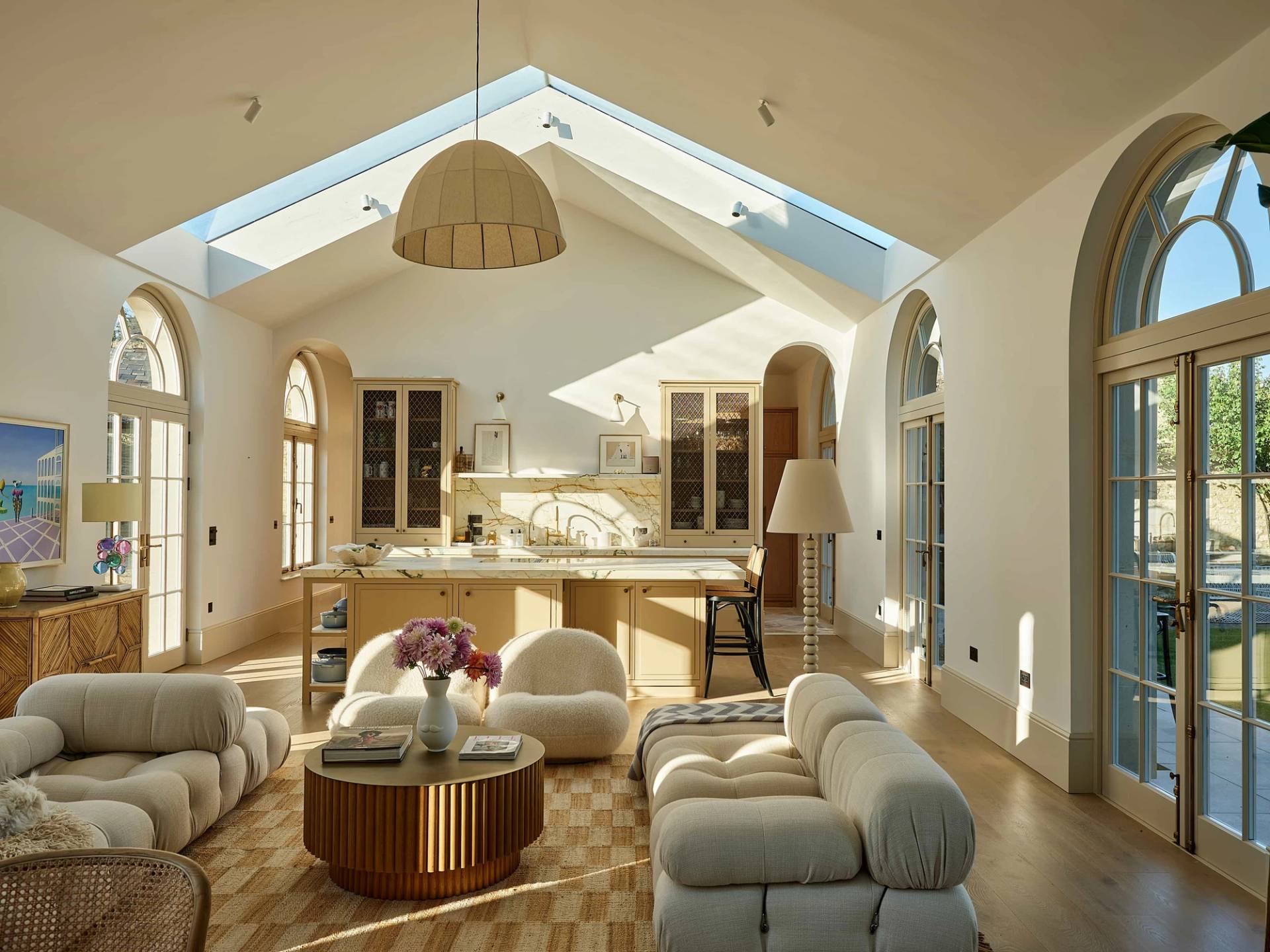 Double-height open-plan reception room with curved cream seating, marble kitchen island, and skylights in a Cotswolds location house, perfect for lifestyle campaigns, Love Locations OX7.