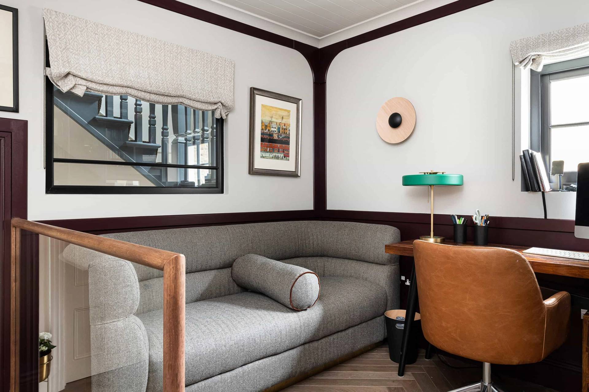 Cozy corner seating nook with a grey curved sofa, dark wood trim, and warm brass lighting, Love Locations.