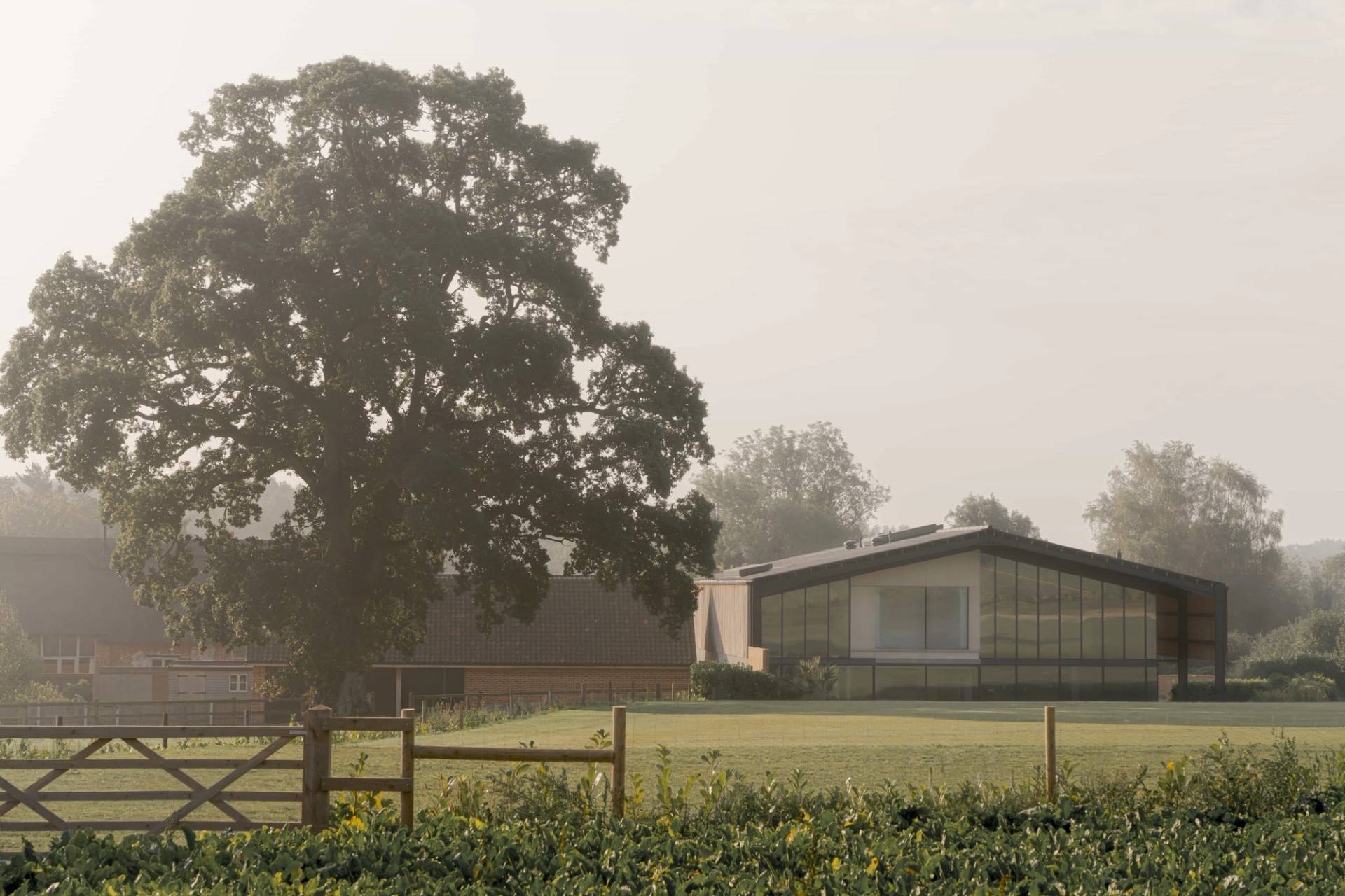 Modern architectural estate shoot location hero cover image in Norfolk, NR9 featuring timber-slatted barn facade, double-height glass reception, luxury indoor pool, games hall, and surrounding country fields, the ultimate high-visibility backdrop for feature film productions, TV commercials, automotive brand campaigns, and luxury fashion editorials via Love Locations.