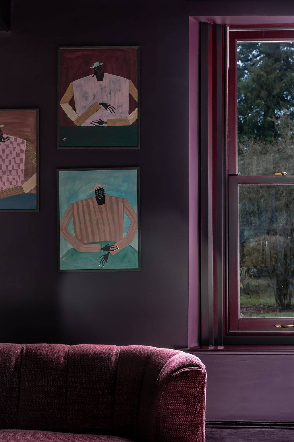 Close-up detail of dark crimson walls adorned with abstract portrait artwork, a rich textual interior backdrop curated by Love Locations.