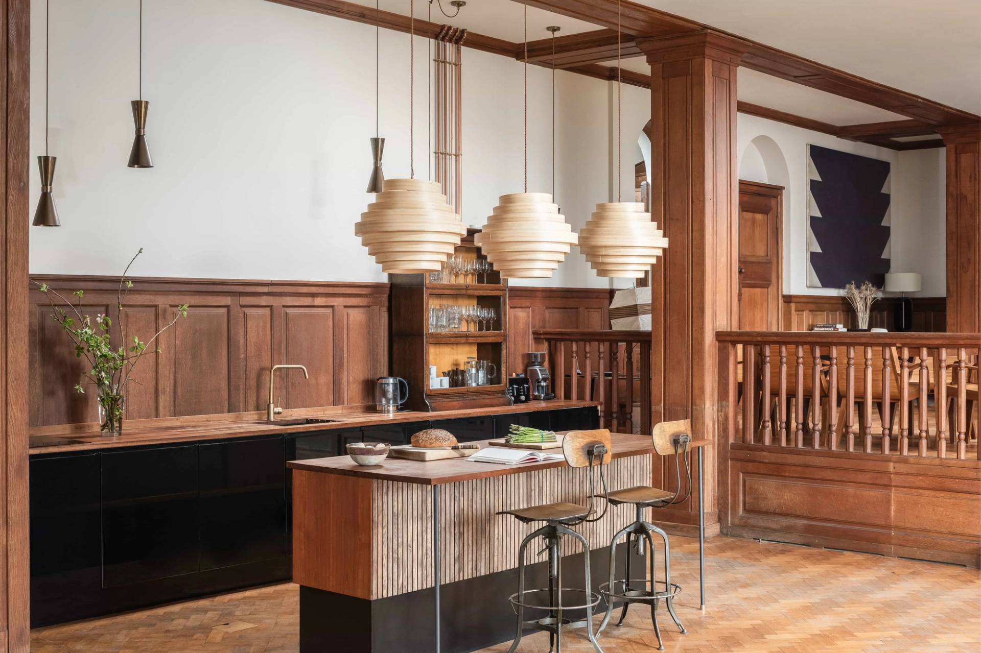 Period kitchen and bar counter shoot location in Totnes Devon TQ12 via Love Locations, showcasing warm timber wall panelling, woven pendant lamps, and parquet flooring.