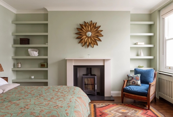Light green bedroom film location in Westminster SW1V available through Love Locations, featuring a traditional fireplace mantle, a sunburst mirror, and built-in alcove bookshelves.