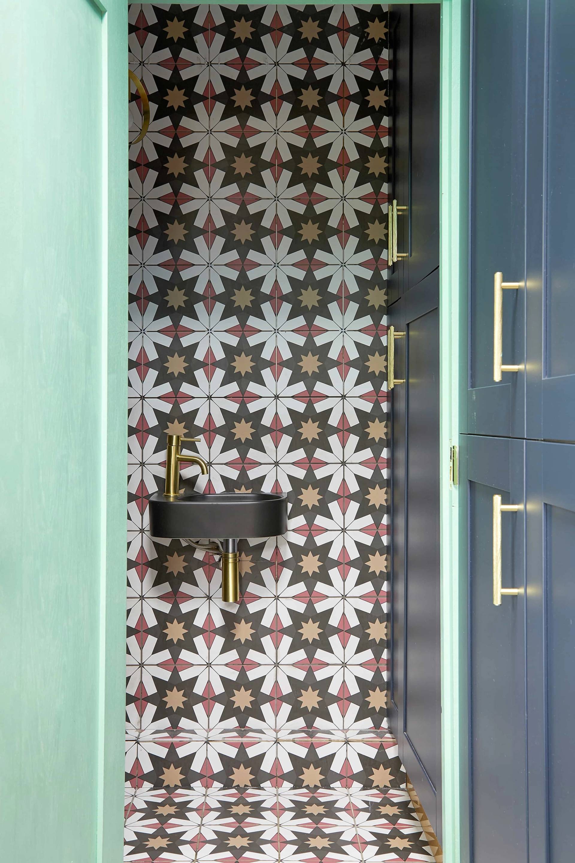 Utility room featuring dark teal cabinets, star-patterned floor tiles, and a black wall-mounted sink, Love Locations Catford.