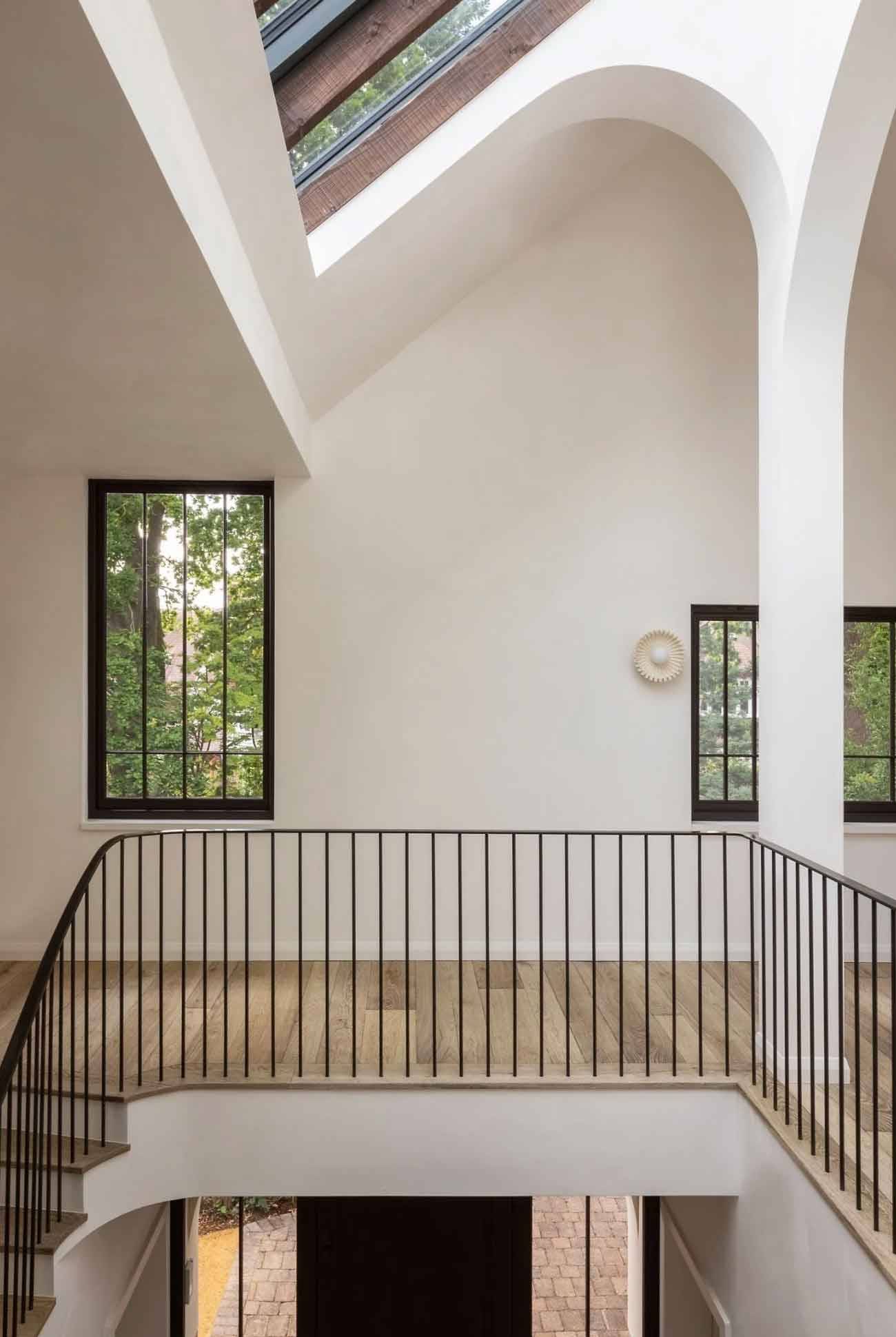 Upper floor gallery landing featuring a curved metal balustrade, skylights, and arched doorway partitions, ideal for fashion editorial photography, Love Locations N6.