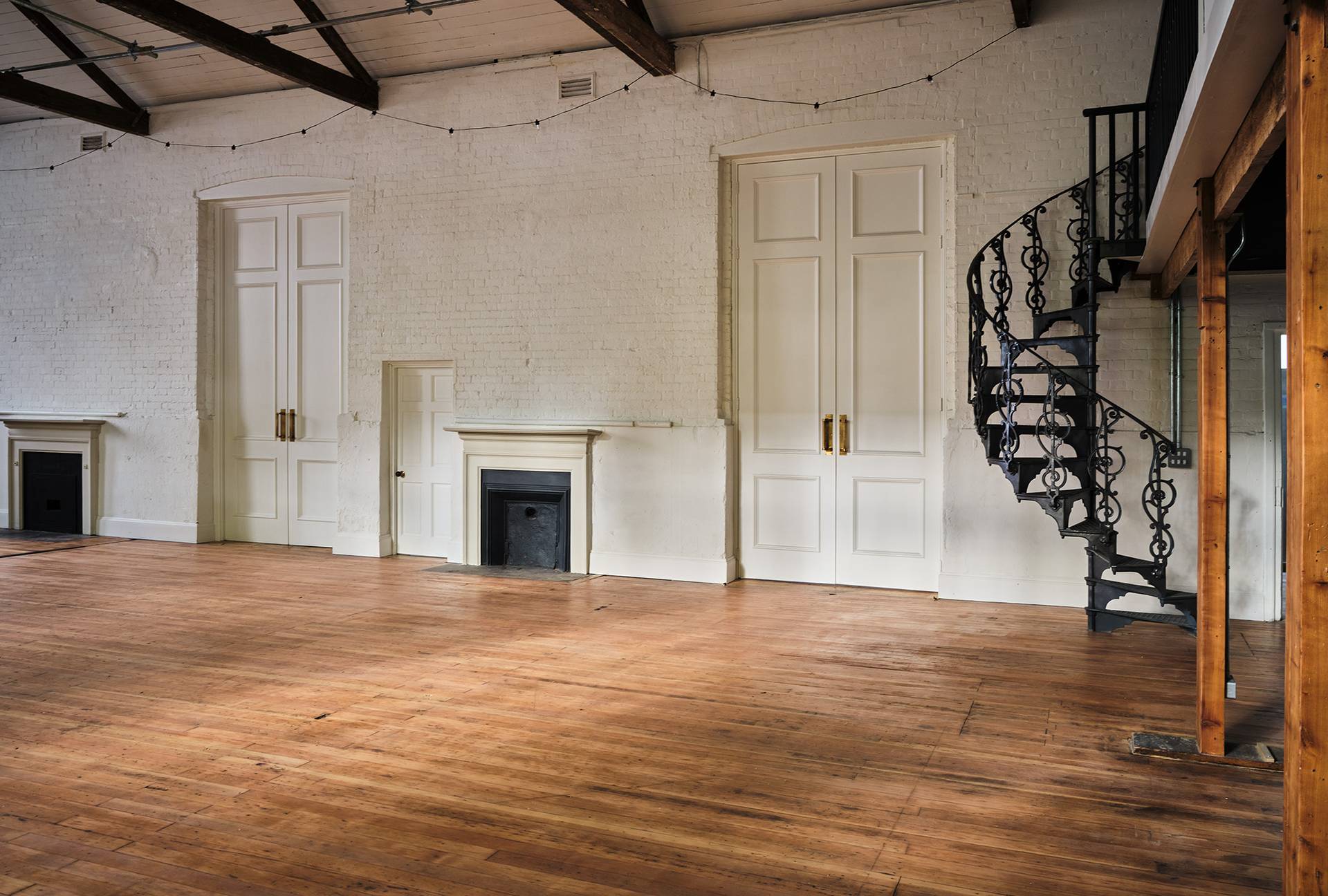 Spacious white hall room with double doors, period fireplace, and black metal spiral staircase, ideal for event photography, Love Locations E2.