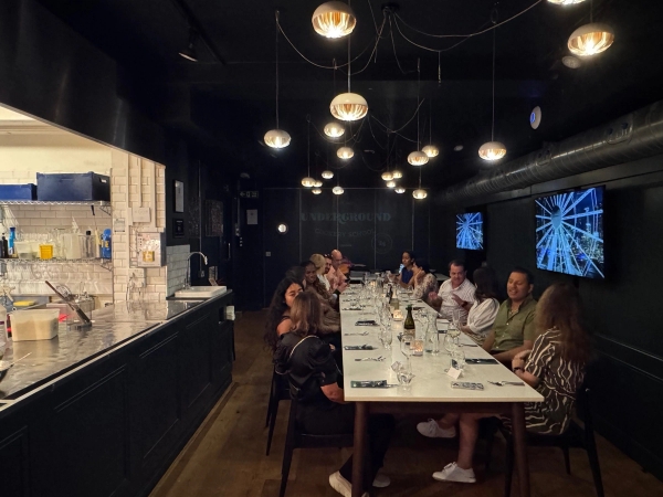 Intimate dinner party or corporate banquet set inside a stylish black-walled London venue hall, managed by Love Locations.