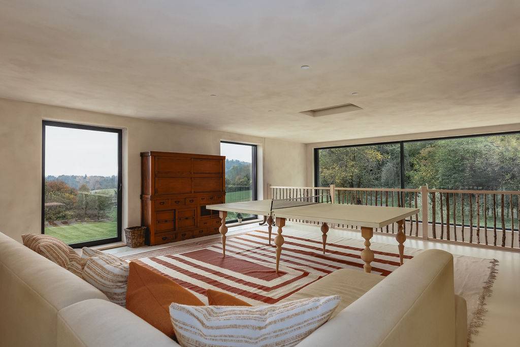 Upper-level games room featuring a table tennis ping pong table, striped rug, and large garden windows, Love Locations GU32.