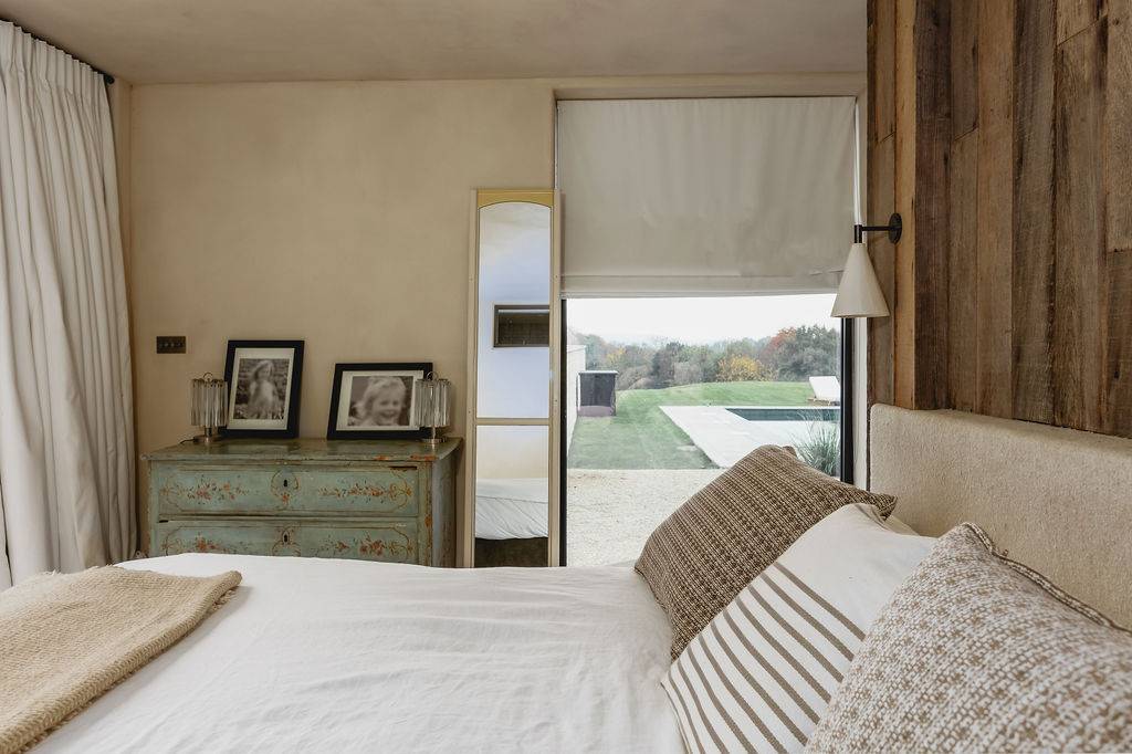 Bedroom view framing a patio glass door that opens directly onto an outdoor terrace and pool, Love Locations GU32.