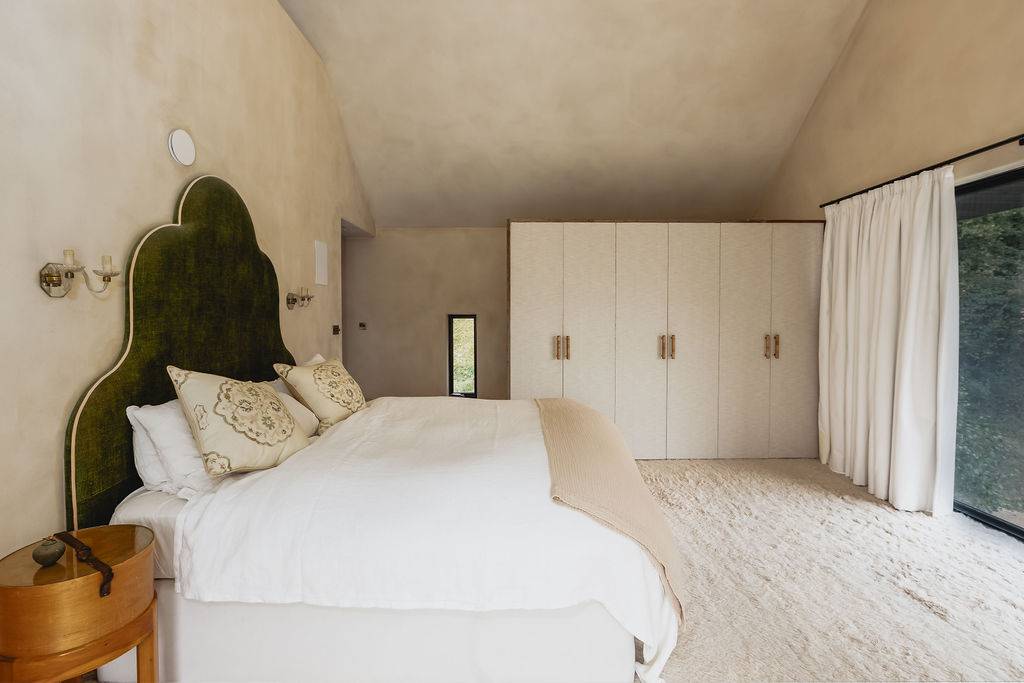 Spacious master bedroom with neutral carpets, fitted white wardrobes, and sloped ceiling light, Love Locations GU32.